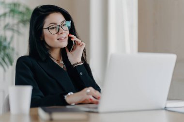 Kendine güveni tam bir iş kadını arıyor, iş yerinde dizüstü bilgisayarla poz veriyor, gözlük takıyor, araştırma yapıyor..