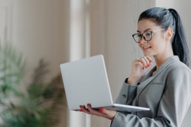 Odaklanmış esmer serbest yazar dizüstü bilgisayarda finans eğitimi alıyor, yayın hazırlıyor, becerilerini geliştirmek için webinars izliyor..