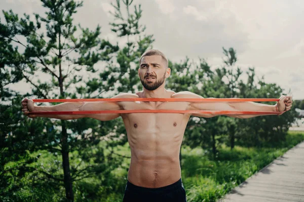 胸のあるスポーツマンは伸縮性の拡大を伸ばし 強い筋肉を構築し 屋外でポーズ — ストック写真