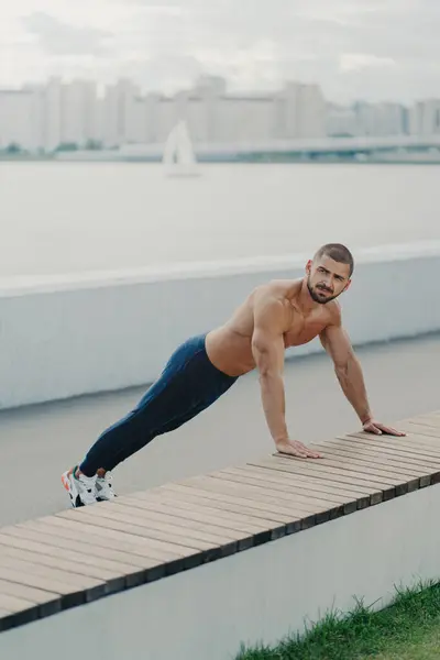 筋肉の男は屋外で暖まり 裸の胴を持つ板は 野外運動を楽しんで 活力のために積極的に身に着けています — ストック写真