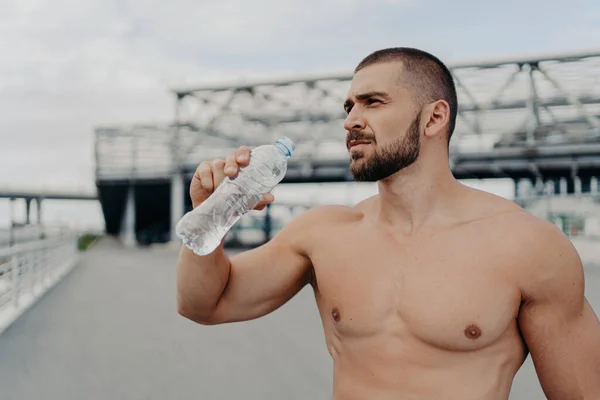 筋肉の男は休憩を取り 水を飲み 水分補給を気にし ジョギングの後に外にポーズ — ストック写真