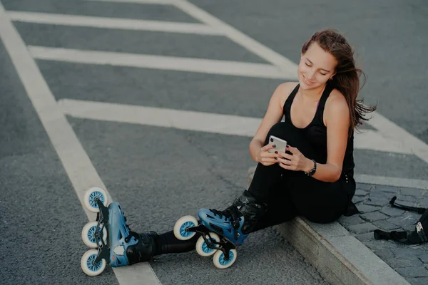 활발히 활동하는 여성은 아스팔트 위에서 스마트폰을 사용하여 온라인 의사소통을 취미와 — 스톡 사진