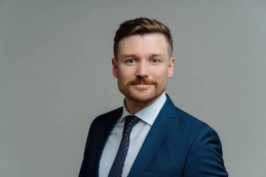 Resmi giyinmiş ciddi sakallı erkek yönetici gri arka planda poz veriyor. Yakışıklı işveren iş görüşmesi için hazırlandı. Görev konsepti.