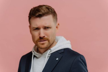 Kafası karışmış adam kaşlarını çatıyor, kötü bir şeyden şüpheleniyor, tozlu gül arka planında izole edilmiş.