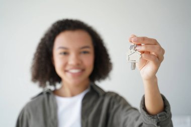 Mutlu çift ırklı genç ev sahibi yeni ev anahtarlarını gösteriyor. Gülümseyen kadın dairenin anahtarını tutuyor, eline odaklan. İpotek reklamı.