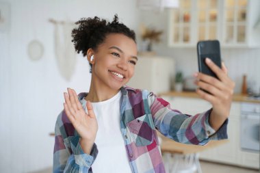 Karışık ırk blogcusu merhaba diyor, internette telefonla sohbet ediyor. Kulaklıklı gülümseyen bayan arkadaşlarını selamlıyor..