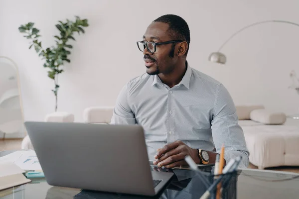 Предприимчивый Афроамериканский Бизнесмен Очках Работает Ноутбуке Размышляет Над Проектом Сидя — стоковое фото