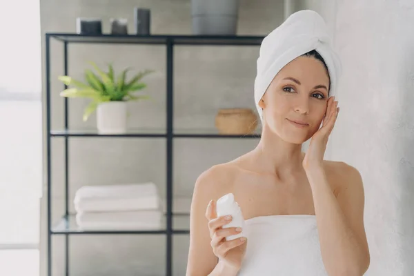 ヨーロッパの女性は 入浴後にタオルで顔化粧水 魅力的な女の子を適用します スパリゾート 顔の保湿剤 リフティングクリーム — ストック写真