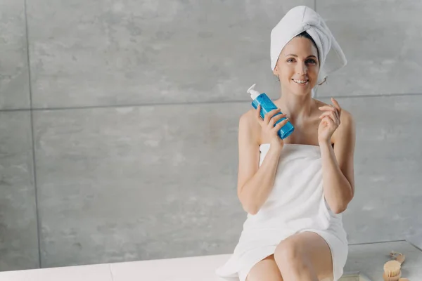 豪華なヨーロッパの女性は タオルで包まれた後風呂 フェイストナー広告バナーでスペースをコピーします 笑顔の女性は マイクロボトルを保持しています 瓶の中の洗顔フォーム — ストック写真