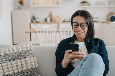 Mutlu kadın mobil uygulama kullanıyor, internetten alışveriş yapıyor, telefonda sohbet ediyor. E-ticaret, e-bankacılık.