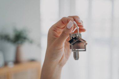 Kadının elinde evin anahtarları var, yeni evi sembolize ediyor. Emlakçı satılık ya da kiralık daireler veriyor. İpotek ilanı.