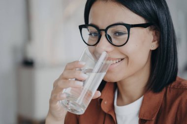 Bardaklı mutlu kadın bardaktan temiz, filtrelenmiş su içer. Su kaybını önler, su dengesini sağlar ve sağlıklı cilde iyi gelir..