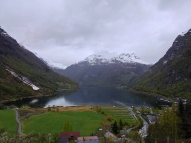 Yağmurlu bir günde arka planda kar örtüsü dağlarıyla Geirangerfjord