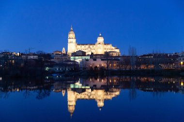 Salamanca, Spain - 7 January 2021: Panoramic view of Salamanca cathedral at night reflected in the river Tormes clipart