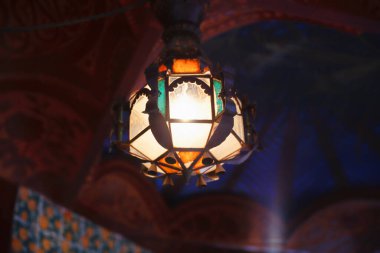 Casa Vicens, Barcelona, Ekim 2023: Tavandan sarkan ve Gaudi 'nin baş yapıtına sıcak ışık saçan karmaşık tasarlanmış bir lambanın yakın çekimi.