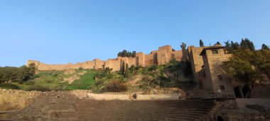 Alcazaba, Malaga, İspanya - 23 Şubat 2023: Taş duvarları ve çevreleyen yeşillikleriyle antik kaleyi gösteren manzara.