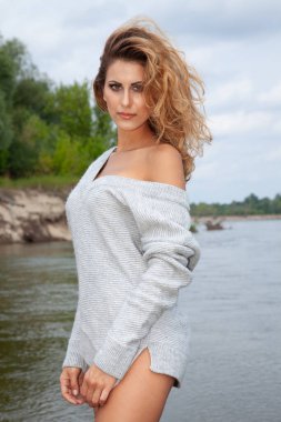 Gri kazaklı çekici sarışın kadının göldeki portresi.