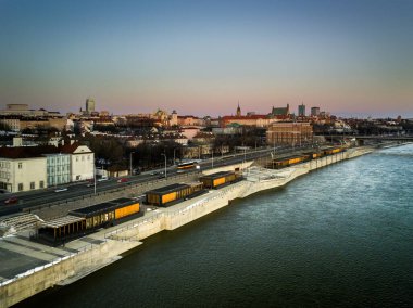 Şafak vakti Vistula Nehri ve modern bulvarlarla Varşova 'nın panoramik manzarası. Tarihi Eski Şehir ve Kraliyet Şatosu, şehrin modern ve tarihi mimarisini harmanlayan yumuşak sabah ışığıyla aydınlanır..