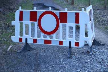 Ortasında beyaz daire olan kırmızı ve beyaz bir tabela. Tabela çakıl yolunda.