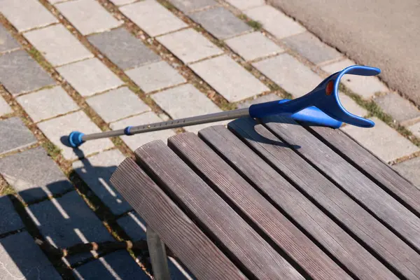 Mavi bir baston ahşap bir banka yaslanıyor. Yedek kulübesi ahşap ve içinde birkaç çatlak var.