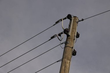 Üzerinde kablolar olan uzun tahta bir direk. Gökyüzü bulutlu ve görünen tek şey kutup.