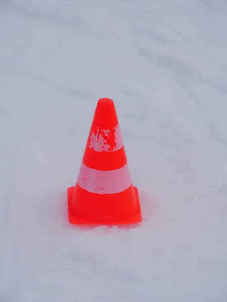 Karda turuncu ve beyaz şeklinde bir koni duruyor. Koni kara yerleştirilir ve görüntüdeki tek nesne odur..