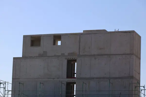 Yan tarafında pencere olan büyük bir bina. Bina tamamlanmamış ve etrafında bir sürü iskele var.. .