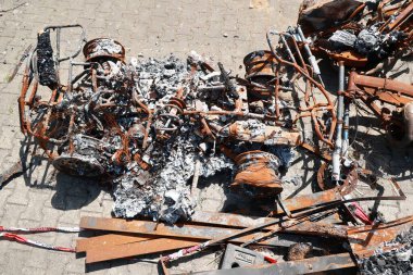 Bir araba hurdalıkta bir sürü döküntü ve paslı parçalarla doludur. Araba hurdaya dönmüş ve yakılmış durumda. Sahne kaotik ve rahatsız edici.