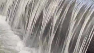 Sisli ve bulanık görünen bir şelale. Su kayalık bir uçurumdan aşağı akıyor, hareket ve güç hissi yaratıyor. Bu sisli etki, sahneye bir gizem ve merak katıyor.