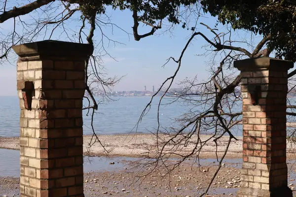 Okyanusa bakan iki tuğla sütun sahilde duruyor. Sütunlar boş ve kumsal sessiz.