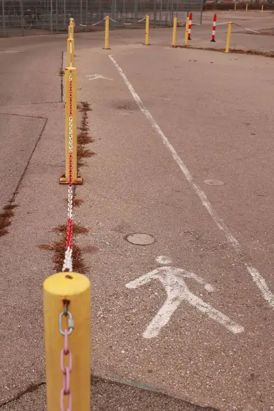 Üzerinde yürüyen bir adam olan sarı ve beyaz tabela yerde. Tabela sarı ve beyaz bir direğin yanında.