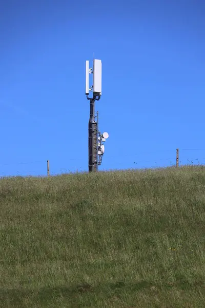 Üstünde baz istasyonu olan uzun bir direğe. Gökyüzü mavi ve berrak. .