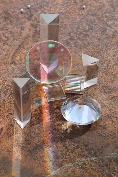 Elmas da dahil olmak üzere cam nesneler kahverengi bir yüzeye yerleştirilmiştir. Nesnelerin hepsi açık ve ışığı yansıtıyor, gökkuşağı etkisi yaratıyor. Güzellik ve merak kavramı