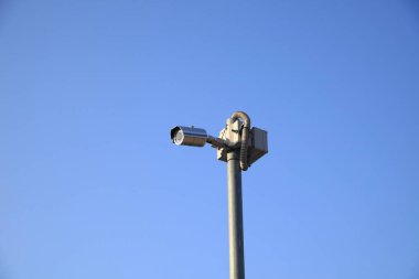 Kamera gökyüzündeki bir direğe monte edilmiştir. Gökyüzü açık ve mavi. Kamera yere dönük.