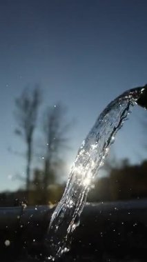 Musluktan akan su akıntısı. Su berrak ve gökyüzü mavi.