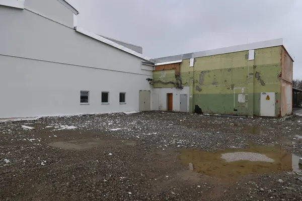 Yeşil duvarı ve beyaz çatısı olan bir bina. Bina boş ve üzerinde bir sürü kar var.