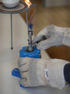 Eldiven takmış ve elinde mavi bir nesne var. Eldivenler potansiyel olarak tehlikeli maddelerle ilgilendiğini öne sürdüğü için, kişi büyük olasılıkla obje ile laboratuvar ortamında çalışıyor.