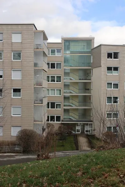 Bir sürü penceresi ve merdiveni olan yüksek bir bina. Bina gri ve modern görünümlü.