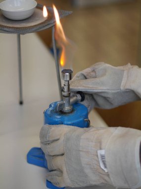 Kişi üzerinde alev olan mavi bir nesne tutuyor. Eldiven takıyor.