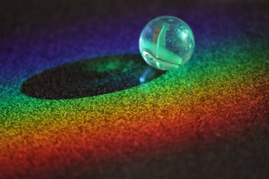 Küçük, berrak, yuvarlak top karanlık bir yüzeye oturur. Top bir renk gökkuşağı ile çevrilidir, merak ve sihir hissi yaratır. Sahne bir neşe ve neşe çağrıştırıyor.