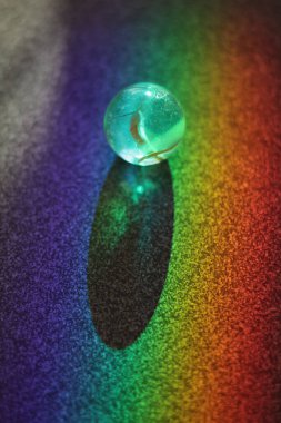 Küçük, berrak, mavi top renkli bir yüzeye oturur. Top renkli bir gökkuşağı ile çevrilidir, canlı ve neşeli bir atmosfer yaratır. Eğlence ve neşe kavramı