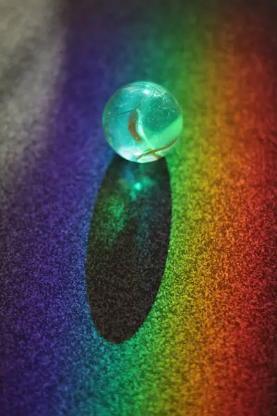 Küçük, berrak, mavi top renkli bir yüzeye oturur. Top renkli bir gökkuşağı ile çevrilidir, canlı ve neşeli bir atmosfer yaratır. Eğlence ve neşe kavramı