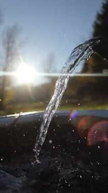 Bir musluktan su akıntısı akıyor. Su berrak ve güneş onun üzerinde parlıyor. Güzel ve huzurlu bir manzara yaratıyor.