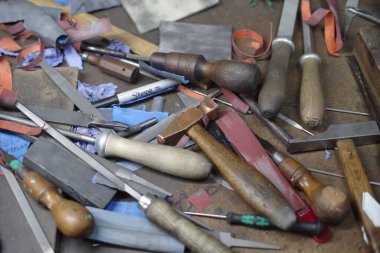 Çeşitli bıçaklar ve makaslar da dahil olmak üzere bir yığın alet. Yığınlar masanın üstünde ve o dağınık.