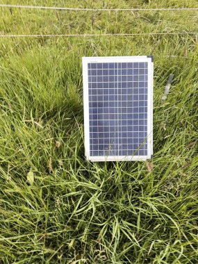 Güneş paneli çimenli bir alanda duruyor. Alan yemyeşil ve yemyeşil. Olay yerindeki tek nesne de güneş paneli.