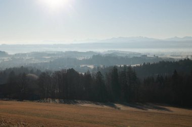 Arka planda geniş bir dağ sırası olan güzel bir manzara. Gökyüzü açık ve güneş parlıyor.