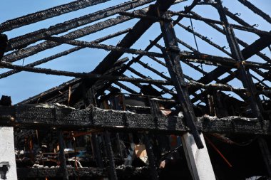 Siyah çatılı ve siyah duvarlı bir bina. Çatı yandı ve bina harabeye döndü.