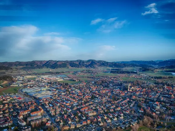 Bir sürü evi ve binası olan şehir manzarası. Gökyüzü mavi ve bazı bulutlar var.