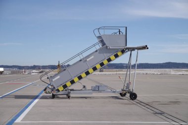 Yerde büyük gri bir merdiven var. Merdiven büyük gri bir kutuya bağlı.