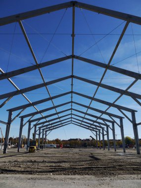 Arka planda mavi gökyüzü olan büyük bir bina. Bina yapım aşamasında ve bir sürü iskelesi var.